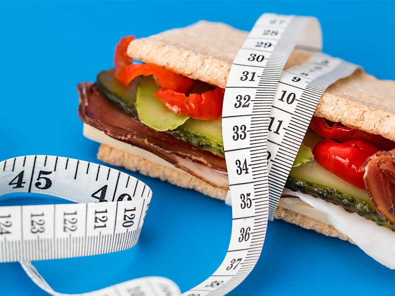 Tape measure round a sandwiched snack to illustrate the choice of seeing a weight management doctor